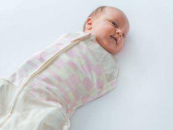 Baby swaddled in Pink Check Sleepea smiling